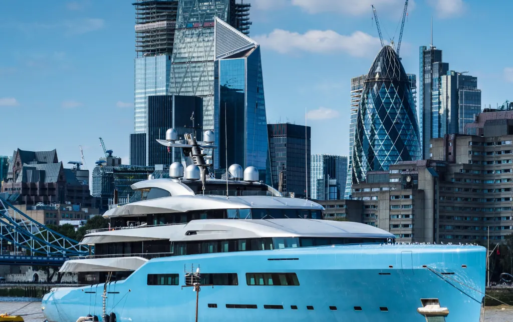 Large yacht in Thames river in front of city of London.