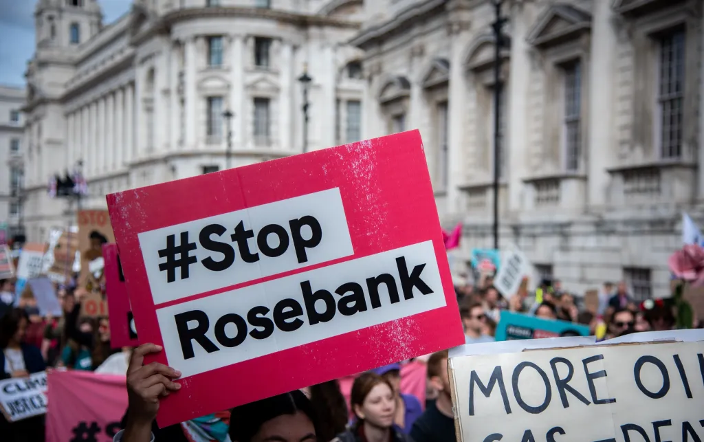 A red sign that has the words '#StopRosebank' on it. Someone is holding the sign during a climate protest.