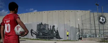 Boy holds football and looks at graffiti 