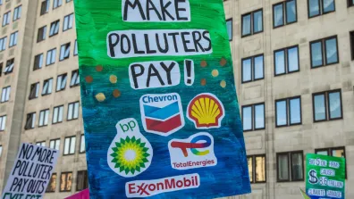 A sign with logos of fossil fuel corporations such as Shell and BP on it. It also has the words 'Make Polluters Pay!' written on it.